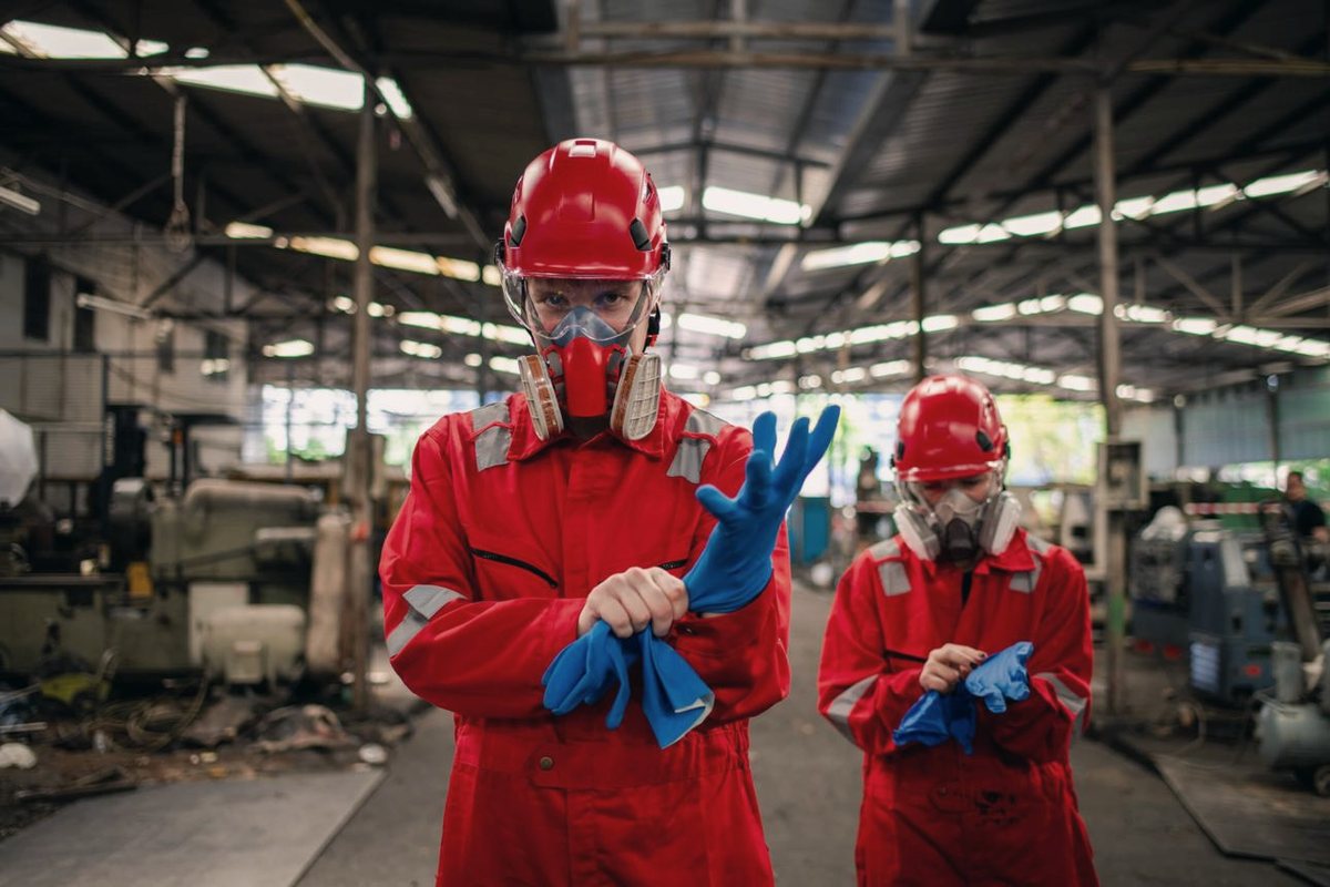 Trabalhadores com equipamento de proteção individual em ambiente industrial insalubre