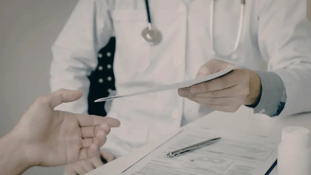 Médico entregando documento ao paciente durante avaliação pericial